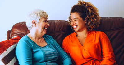 caregiver and senior woman smiling sitting on the sofa